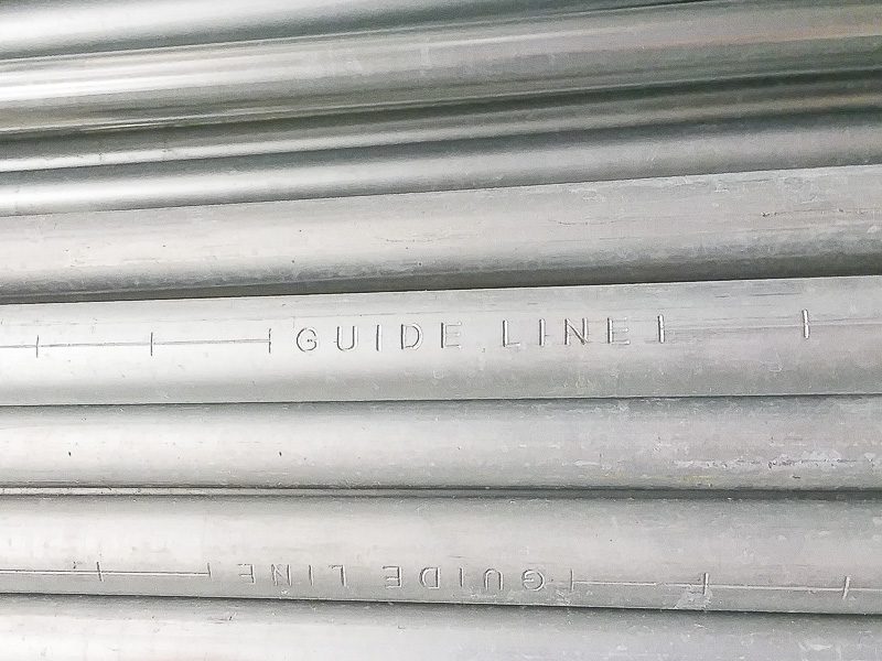 guide lines and inch marks stamped onto EMT electrical conduit