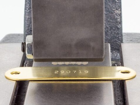 character stamping onto a brass tag with a marking press