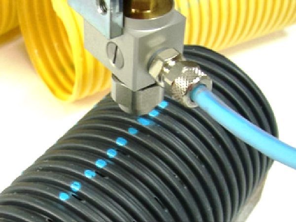 automatic spray head printing a colored stripe on black corrugated pipe