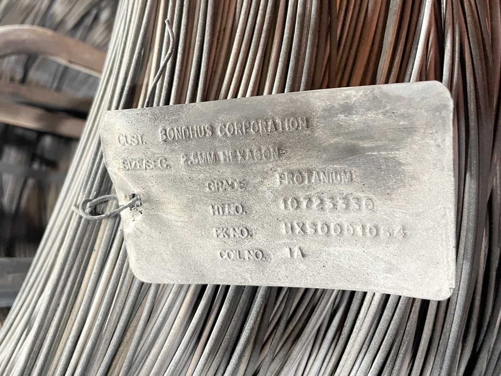 stainless steel tag embossed with order information attached to a spool of wire that has been through harsh acid pickling process